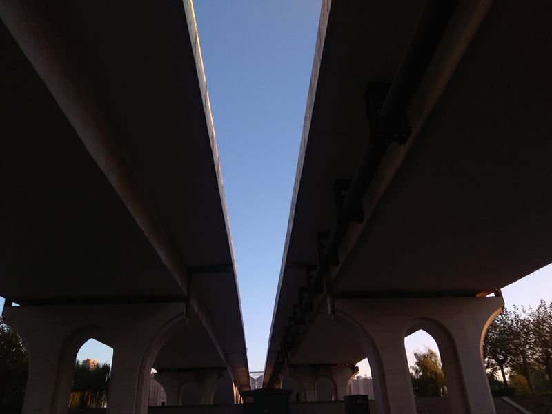 手机拍摄；夕阳余辉照大桥，仰看形成一线天1.jpg